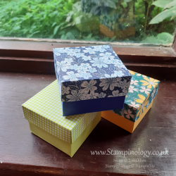 Image is a photograph of three small boxes with patterned paper lids.